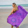 Woman on a beach holding a purple sand free mandala beach towel