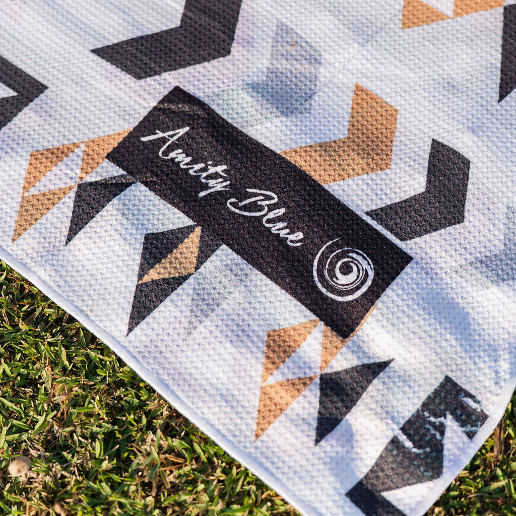 Aztec beach blanket with 'Amity Blue' label on grass