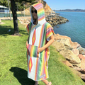 woman wearing an Amity blue large colourful hooded towel made from recycled plastic bottles. Hooded Towel is called into the wild. 