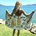 Woman holding a Amity Blue retro patterned towel by the sea.
