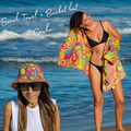 Two women on a beach with colorful Amity blue sand-free beach towel and bucket hat.