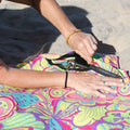 Person zipping up a pocket in a colorful sand-free beach towel